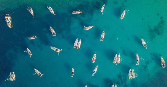 Aerial view of group of sailing boats anchoring on buoys. Bird eye view, water sport theme.