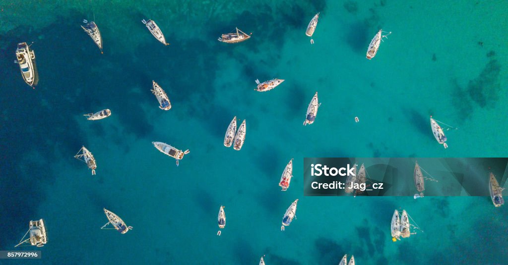 Aerial view of group of sailing boats anchoring on buoys. Aerial view of group of sailing boats anchoring on buoys. Bird eye view, water sport theme. Nautical Vessel Stock Photo