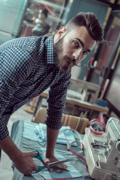 istock Clothes designer in his studio cutting fabric 857976278