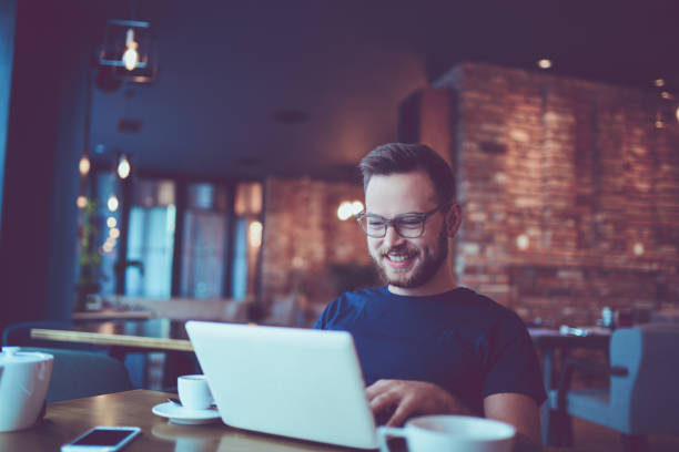 istock Young Smiling Hipster Freelancer Working in a Cafe Restaurant 857993526