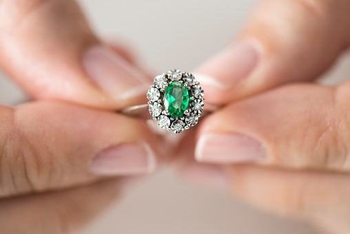 Hands holding diamond. Emerald.