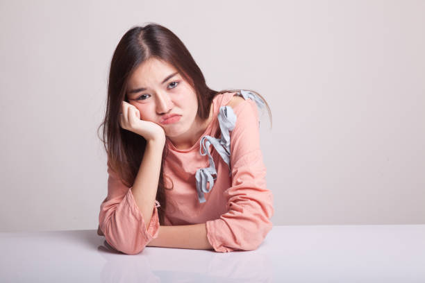 Asian girl is getting bore on gray background