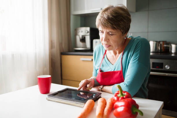 istock Elegant elderly woman using  tablet in the kitchen 857999520