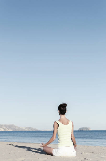 istock Woman practicing yoga on sand beach 858005000