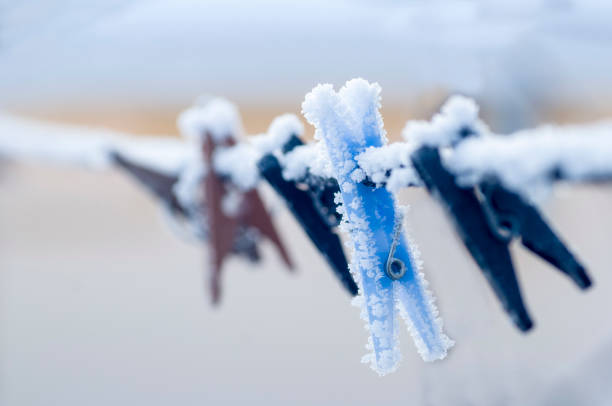 Frozen colorful clothes-pins on a rope at winter morning