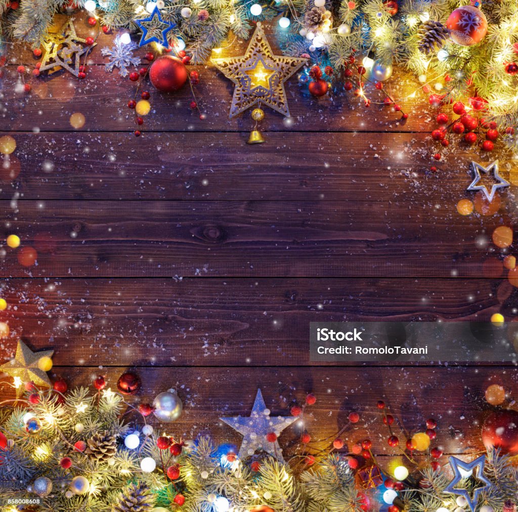 Christmas Background - Snowy Fir Branches And Lights On Dark Table Pine Branches And String Lights On Dark Plank Backgrounds Stock Photo