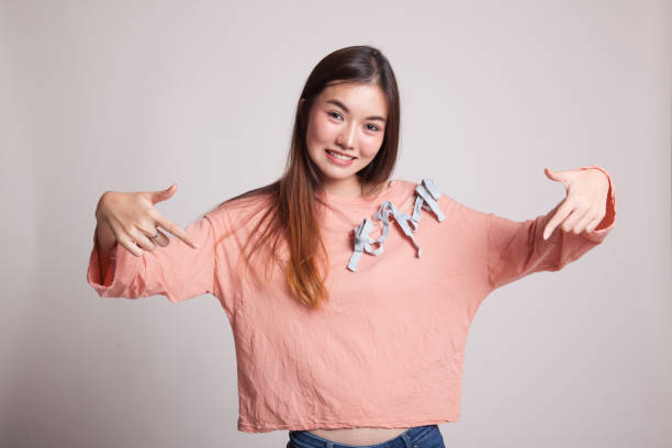 istock Beautiful young Asian woman point down to blank space. 858011472