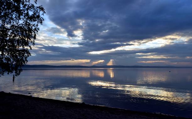 istock sunlight breaking through gray clouds over the lake 858042866