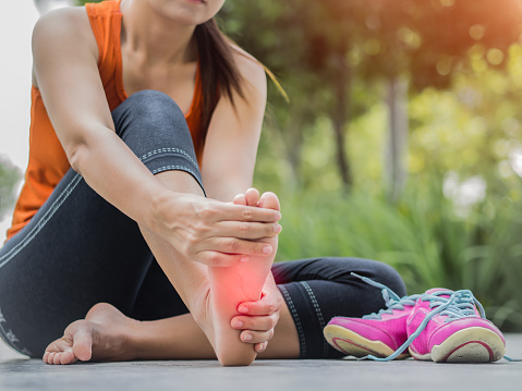 Mujer de enfoque suave masajeando sus pies dolorosos durante el ejercicio.   Ejecutar el concepto de lesión deportiva. photo