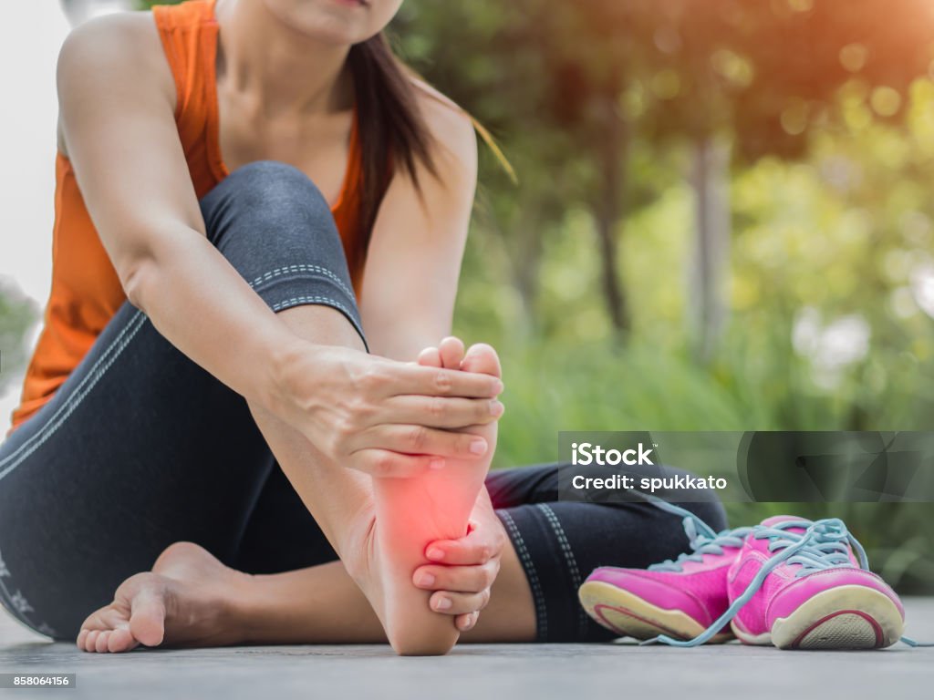 Mujer de enfoque suave masajeando sus pies dolorosos durante el ejercicio.   Ejecutar el concepto de lesión deportiva. - Foto de stock de Pie - Anatomía libre de derechos