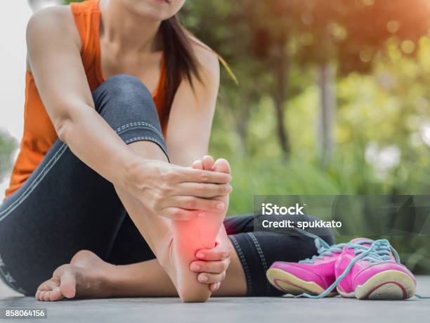 Soft Focus Woman Massaging Her Painful Foot While Exercising Running Sport Injury Concept Stock Photo - Download Image Now