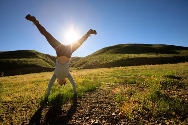 istock woman doing a handstand in a sunrise meadow 858091946
