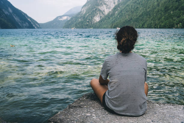 istock Young woman sitting by the beautiful lake 858095014