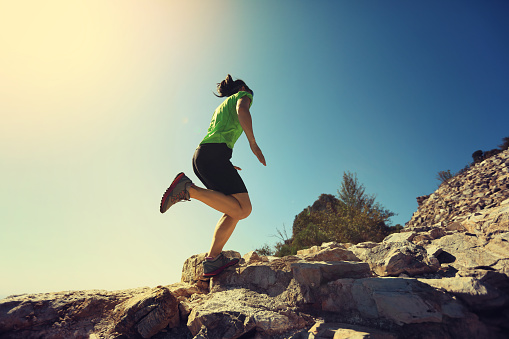 woman trail runner running at mountain top