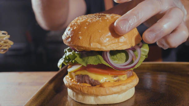 istock Close-up shot of chef's hands preparing a hamburger with beef rissole and cheese 858110020
