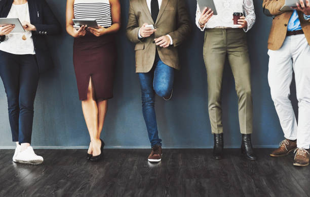 Getting their feet into the door of business Cropped studio shot of a group of businesspeople using wireless technology while waiting in line against a gray background military recruit stock pictures, royalty-free photos & images