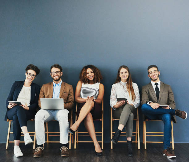 The kind of confidence you want in great candidates Studio portrait of a group of businesspeople using wireless technology while waiting in line against a gray background military recruit stock pictures, royalty-free photos & images