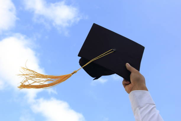 Male hand throwing graduation hat in the air