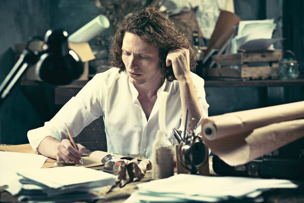 istock Writer at work. Handsome young writer sitting at the table and writing something in his sketchpad 858114974
