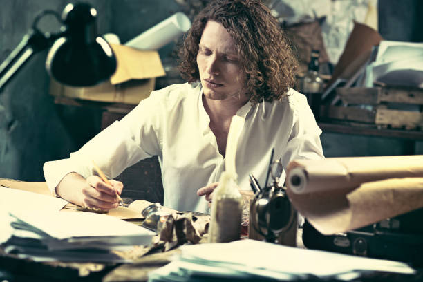 istock Writer at work. Handsome young writer sitting at the table and writing something in his sketchpad 858115048