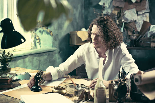 istock Writer at work. Handsome young writer sitting at the table and writing something in his sketchpad 858115270