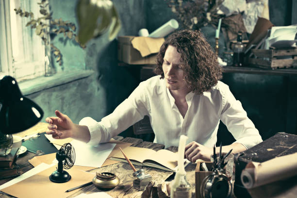istock Writer at work. Handsome young writer sitting at the table and writing something in his sketchpad 858115388