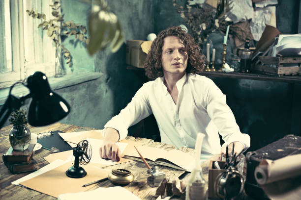 istock Writer at work. Handsome young writer sitting at the table and writing something in his sketchpad 858115430