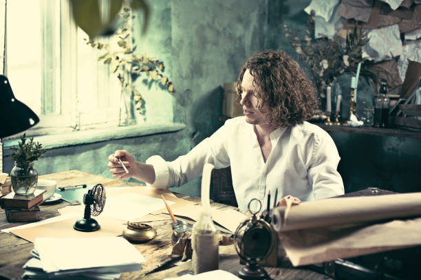 istock Writer at work. Handsome young writer sitting at the table and writing something in his sketchpad 858115476