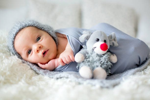 piccolo neonato, guardando curiosamente la telecamera - baby sleeping bedding teddy bear foto e immagini stock