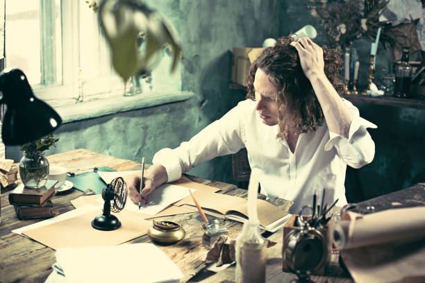 istock Writer at work. Handsome young writer sitting at the table and writing something in his sketchpad 858115534