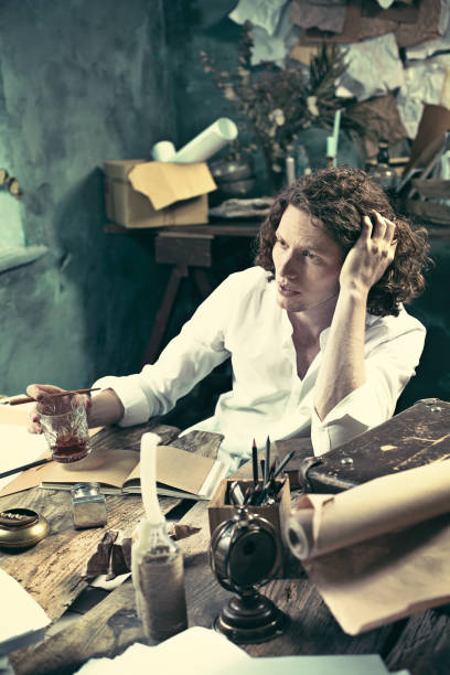 istock Writer at work. Handsome young writer sitting at the table and writing something in his sketchpad 858115720