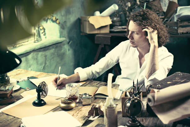 istock Writer at work. Handsome young writer sitting at the table and writing something in his sketchpad 858115866