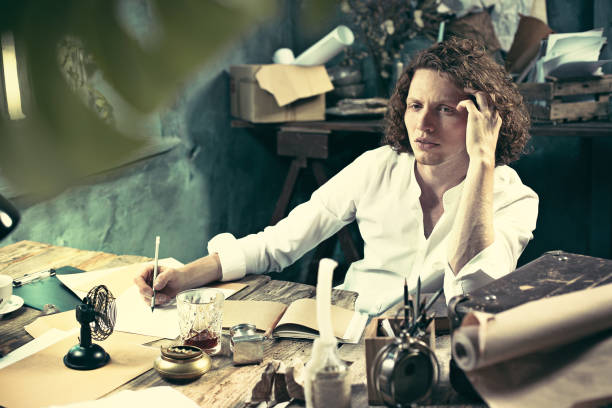 istock Writer at work. Handsome young writer sitting at the table and writing something in his sketchpad 858115900