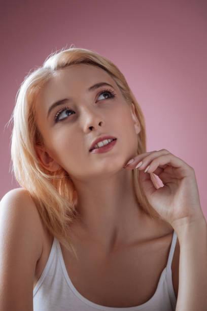 portret enigmatycznej dziewczyny, która jest głęboko w myślach - vertical studio shot indoors pink zdjęcia i obrazy z banku zdjęć