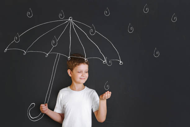 istock Handsome boy under chalk drawing umbrella, held out his hand and catches the raindrops. 858131056