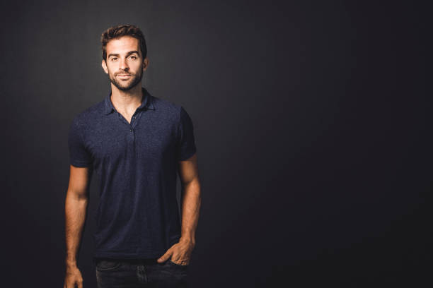 Portrait of handsome man standing against gray background. Fashionable male is with hand in pocket. He is wearing casuals.