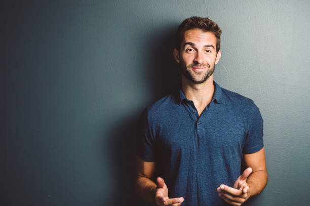 Smiling mid adult man gesturing against gray wall