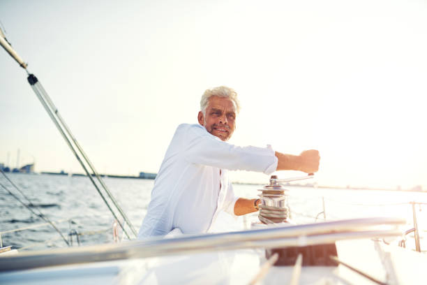 istock Smiling mature man standing on his boat using a winch 858138438