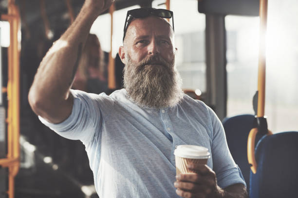 homme mûr, boire du café en se tenant debout sur un bus - coffee to go flash photos et images de collection