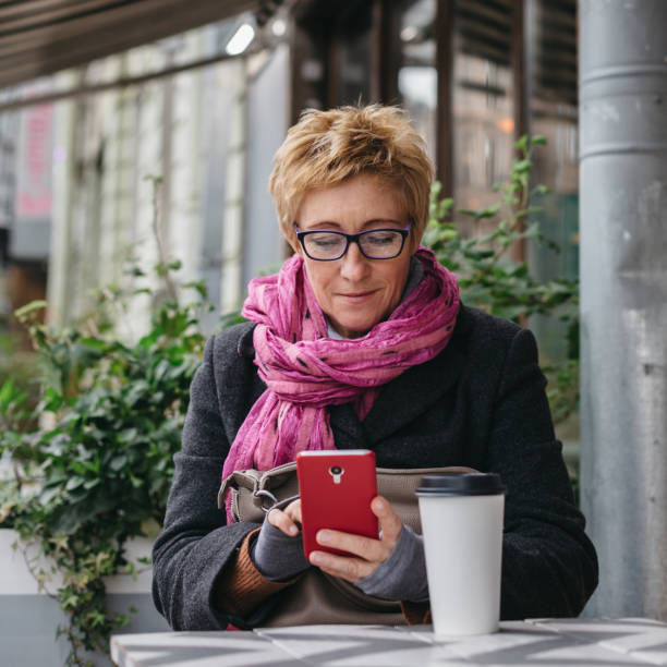 istock Smiling woman with phone in cafe 858143420
