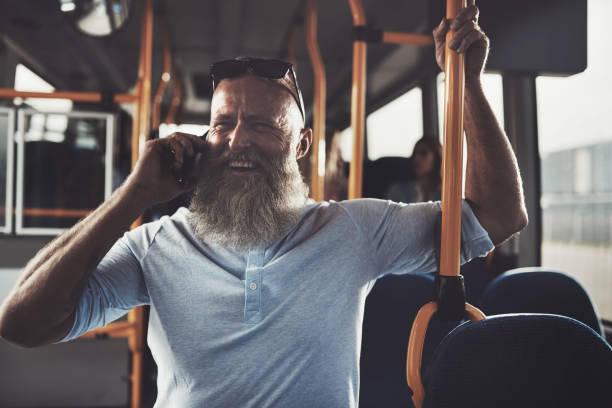 istock Smiling mature man standing a bus talking on his cellphone 858143492