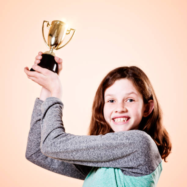 istock Delighted pre-teen holds silver trophy aloft smiling 858143676