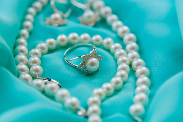 istock Pearl necklace and ring on luxury satin background 858144004