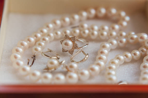 istock Pearl necklace, earrings and ring on luxury satin background 858144242