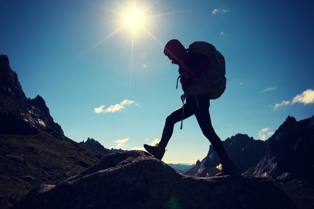 istock successful woman with backpack hiking in sunrise mountains 858144546