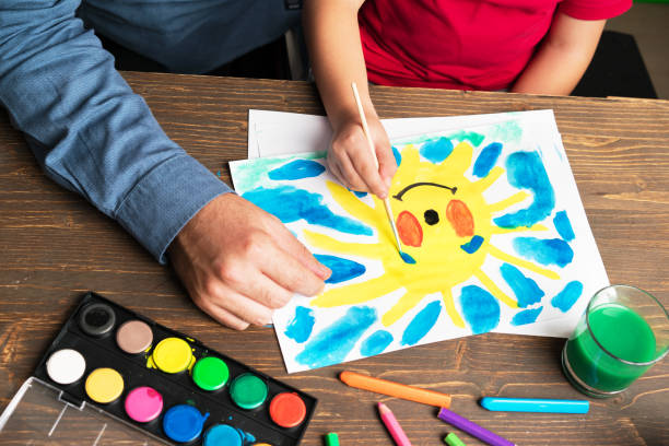 istock Father and son painting a sun with watercolor 858144672