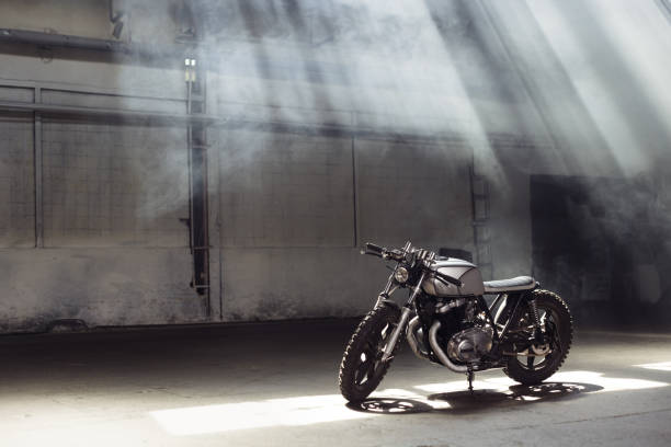 motorcycle standing in dark building in rays of sunlight stock photo