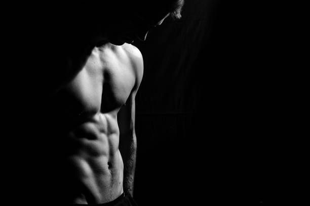 modelo de fitness masculino mostrando os músculos em estúdio com um fundo preto - shirtless strength sensuality black - fotografias e filmes do acervo