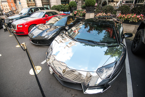 London, UK - Sept 01, 2017: Luxury sport cars parked near Dorchester hotel in London's Mayfair district. Silver Lamborghini Aventador among other luxury cars such as Ferraris, Rolls Royce and Bugatti Veyron are owned by wealthy business people from Middle East.