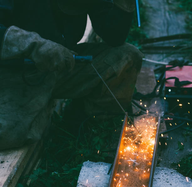 trabalho soldador masculino queima buraco do eléctrodo em aço canal à noite - vending machine flash - fotografias e filmes do acervo